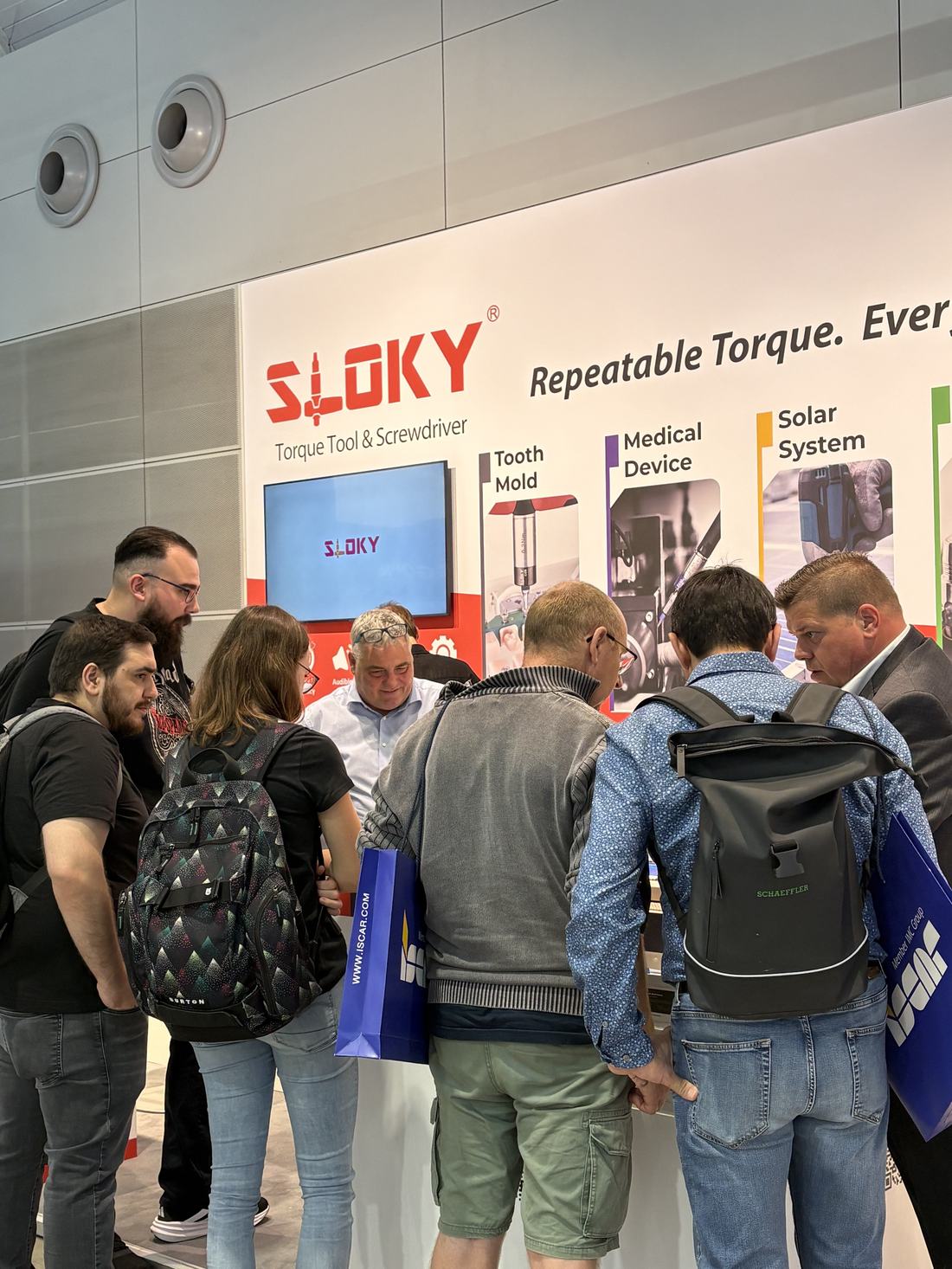 SLOKY Standdisplay mit den Anwendungsbereichen Zahntechnik, Medizintechnik und Solarindustrie, umringt von Besuchern